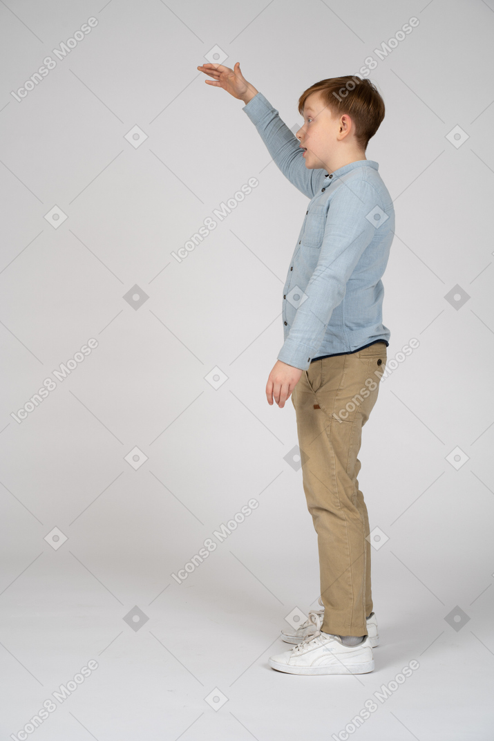 Boy in blue shirt and khaki pants raising his hand