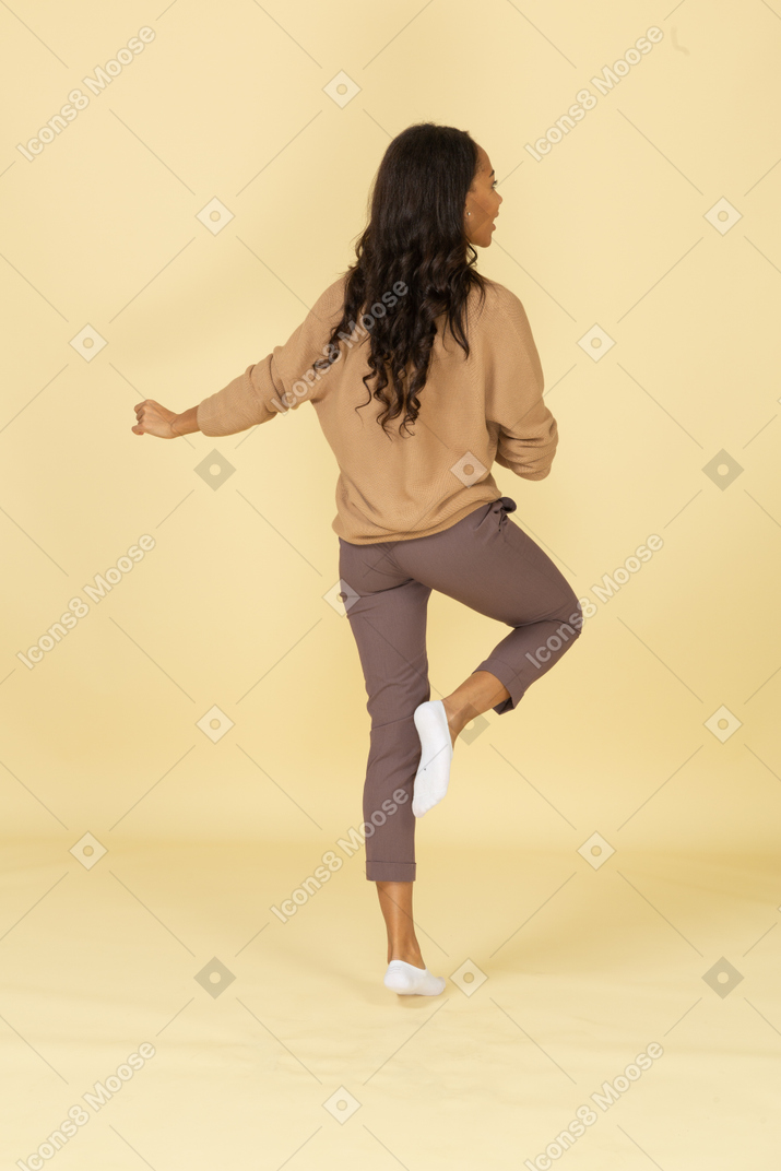 Три четверти сзади марширующей темнокожей молодой женщины, поднимающей ногу