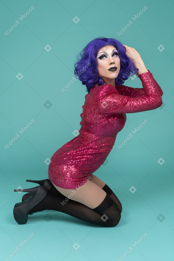 Portrait of a drag queen standing on their knees & holding hands together
