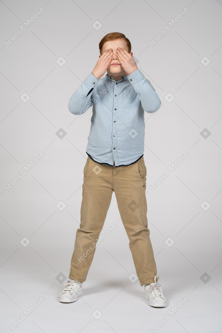 Front view of a boy covering eyes with hands