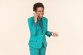 Молодая негритянка с короткой стрижкой позирует в синем наряде с мобильным телефоном в руке