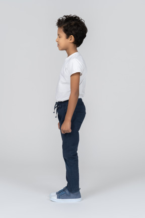 A boy standing with hands alongside body