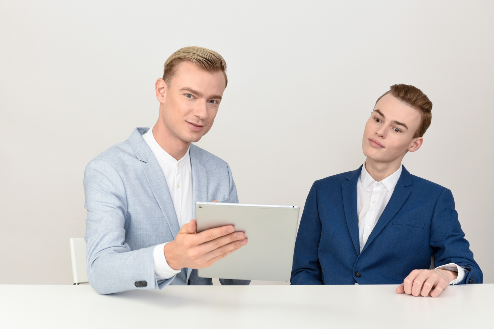 Two male colleagues looking at tablet and talking about work