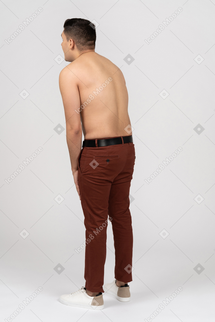 Three-quarter back view of a shirtless latino man hunching a little