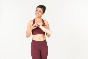 Jeune femme indienne sportswear tenant une bouteille de sport