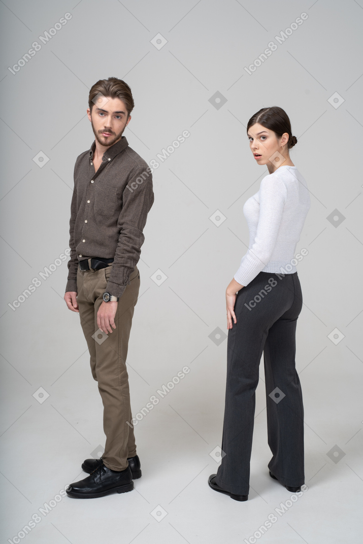 Side view of a surprised young couple in office clothing turning away