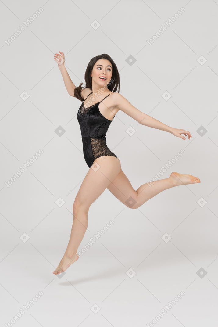Delighted young woman in black lingerie running sideways