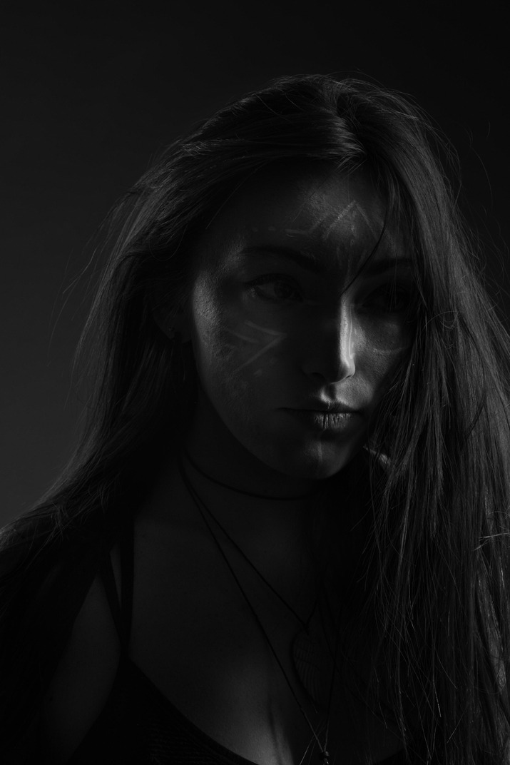 Close-up dark silhouette of a young female with face art looking aside