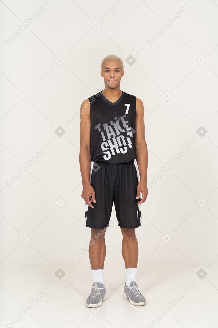 一个年轻的男篮球运动员站着不动 & 压嘴唇的前视图