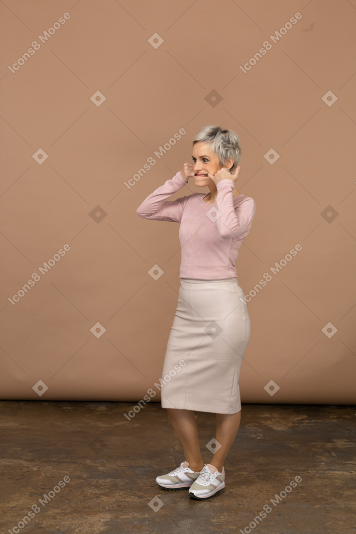 Vista lateral de uma mulher com roupas casuais colocando os dedos na boca