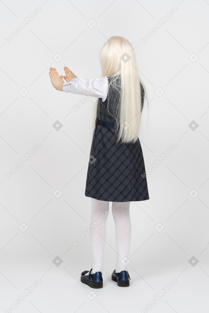 Vista posteriore di una ragazza della scuola con le mani in alto