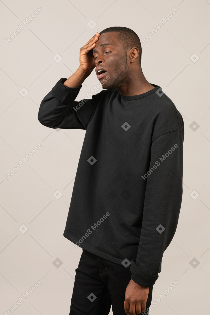 Young man with closed eyes touching his head