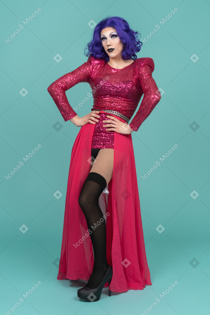 Drag queen in pink dress resting both hands on their waist & leaning backwards