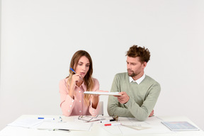 Female and male architects sitting at the table and holding tablet