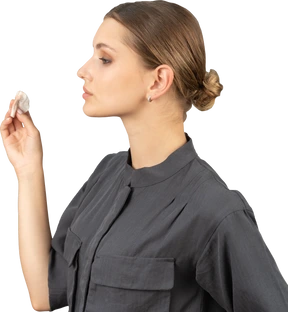 Side view of a young woman in a jumpsuit removing concealer