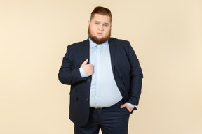 Young overweight man in suit touching jacket with a hand