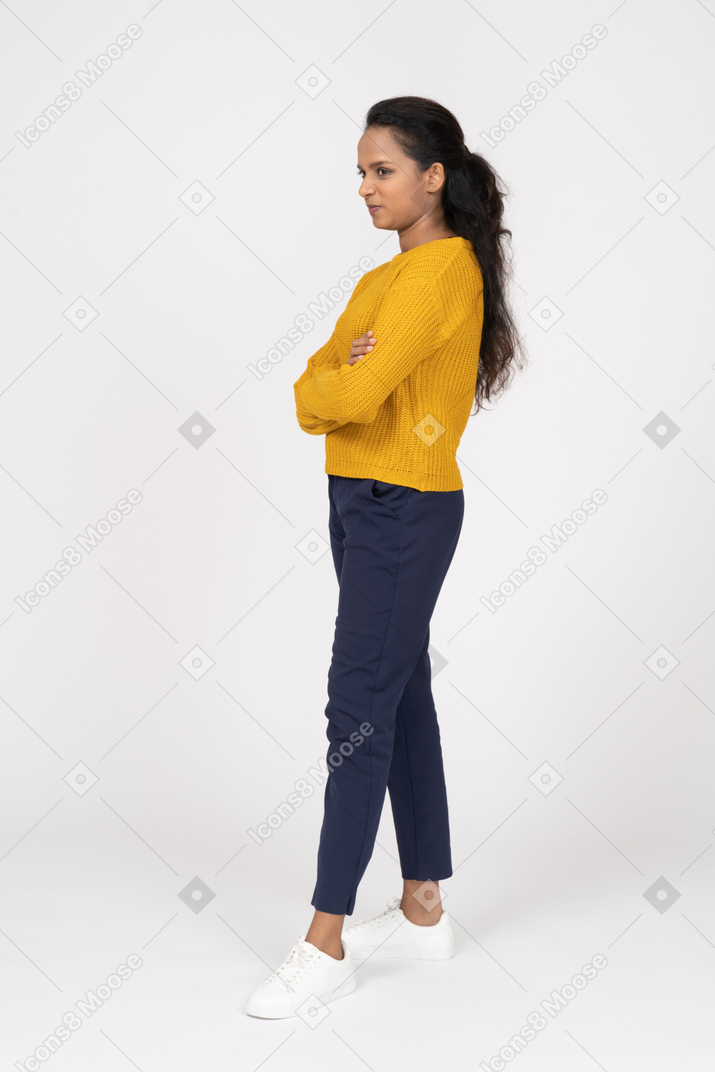 Side view of a girl in casual clothes posing with crossed arms and making faces