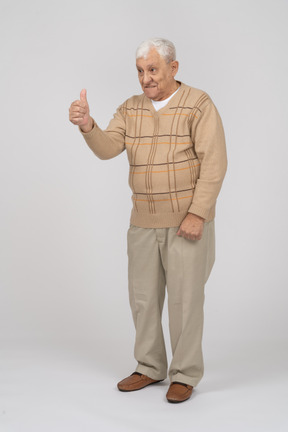 Vista frontal de um velho feliz em roupas casuais, aparecendo o polegar