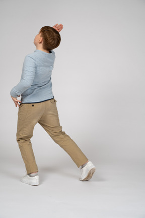 A young boy in a blue shirt putting his foot back