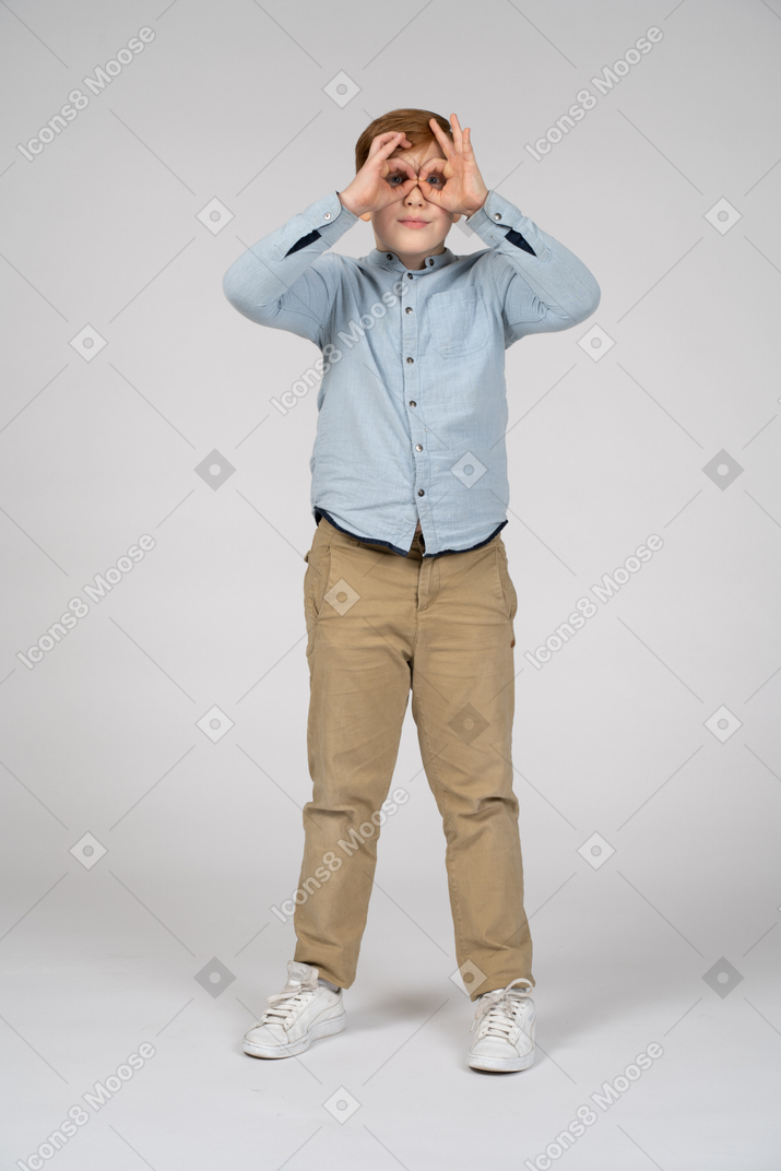 Front view of a boy looking at camera through imaginary binocular