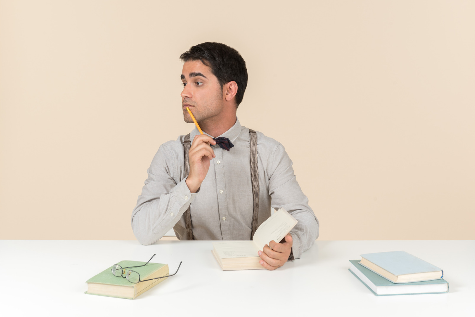Pensive adult student sitting at the table with opened book