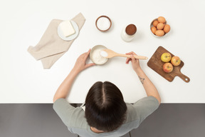 A female baker mixing flour and sugar