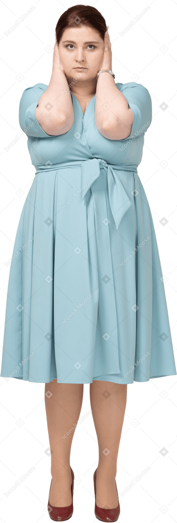 Vue de face d'une femme en robe bleue couvrant les oreilles avec les mains