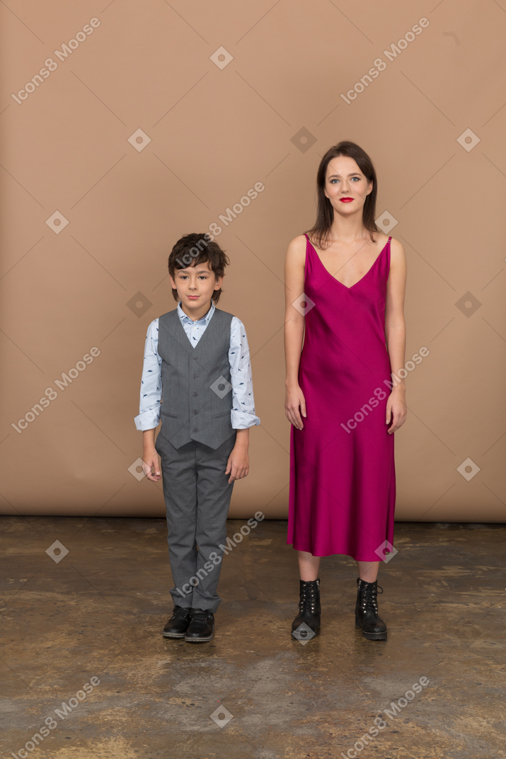 穿着红色连衣裙的女人和微笑的男孩站在一起