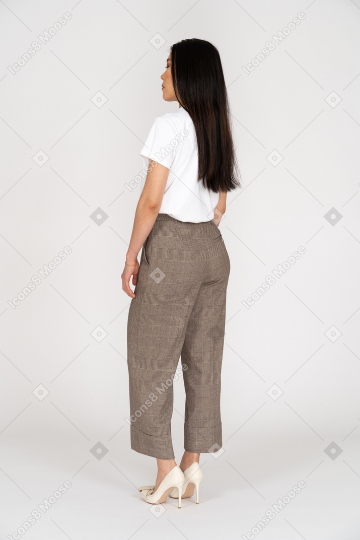 Three-quarter back view of a young woman in breeches standing still with her eyes closed