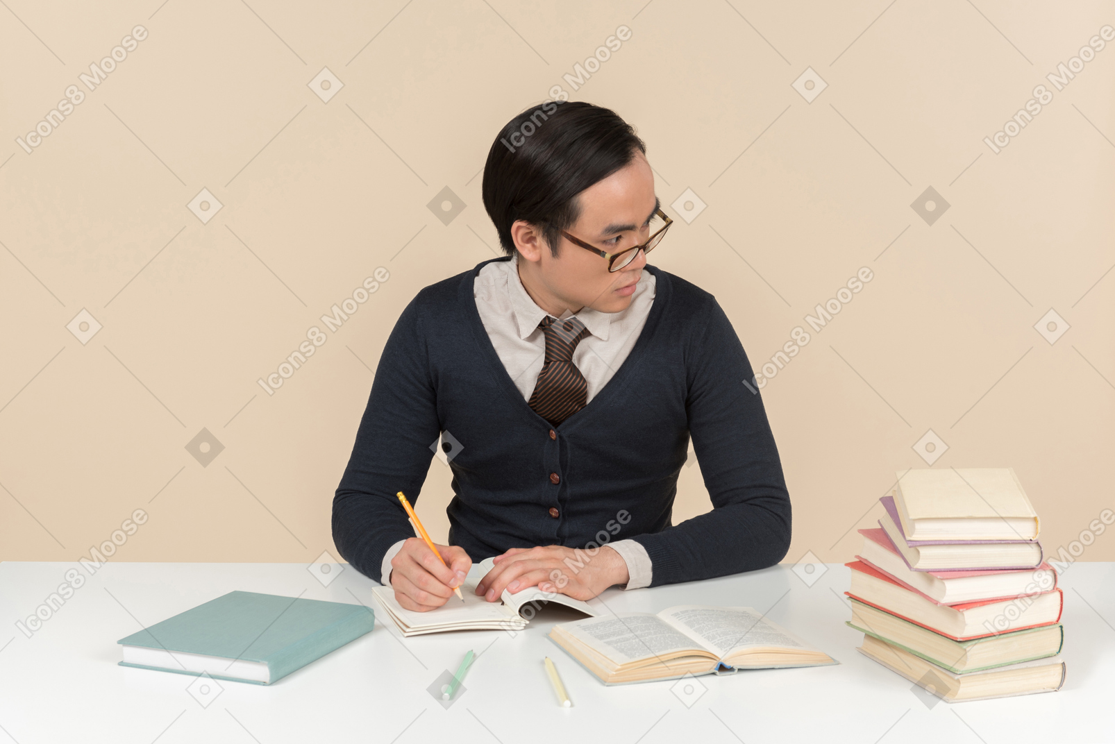 Young asian student in a sweater writing in a notebook
