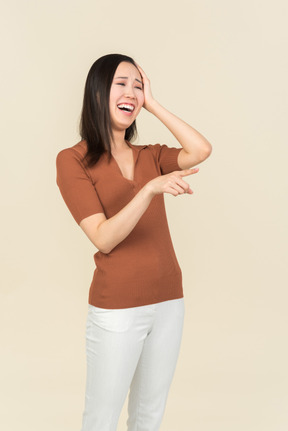 Sorrindo jovem mulher asiática apontando para a frente