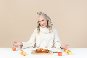 Elegante donna anziana che offre di provare la sua torta di mele appena sfornata