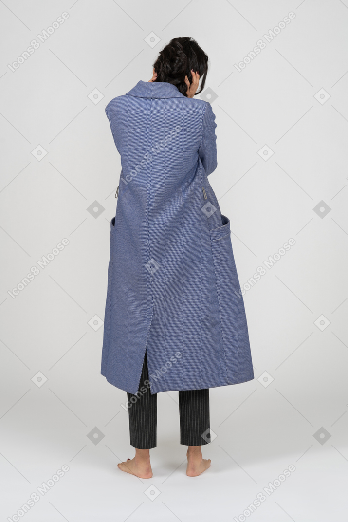 Vista traseira de uma mulher de casaco puxando o cabelo