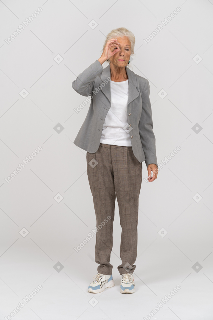 指を通して見ているスーツの老婦人の正面図