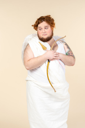 Sad looking big guy dressed as a cupid holding bow