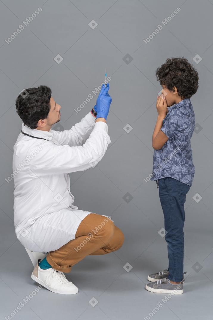 男の子に注射器を見せている医者