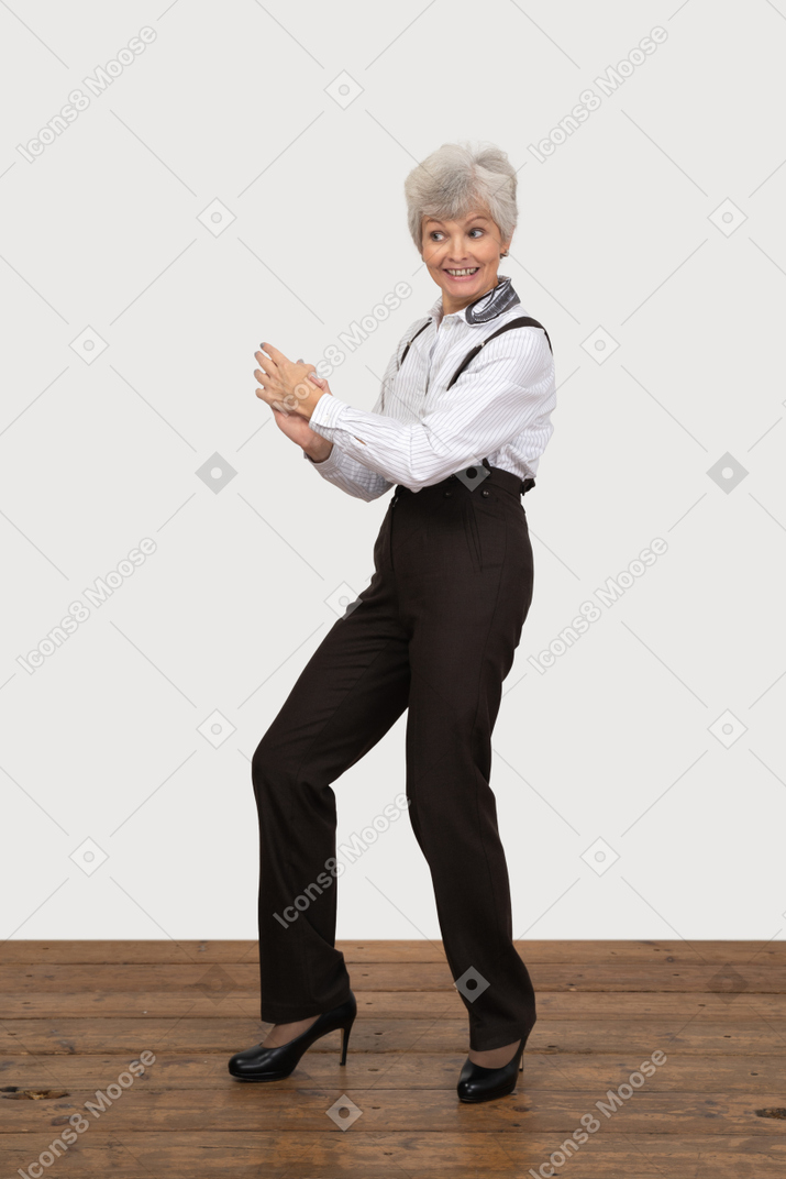 Side view of a cheerful old lady in office clothing holding hands together