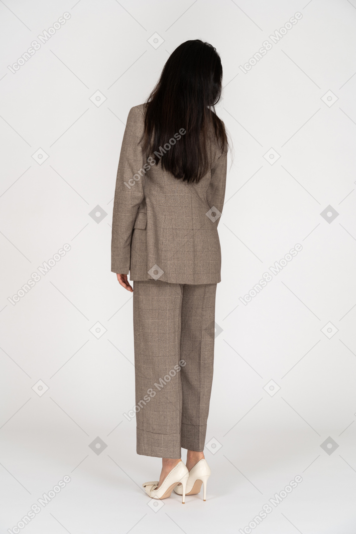 Three-quarter back view of a young lady in brown business suit looking aside