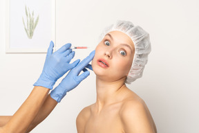 Woman looking terrified during filler injection