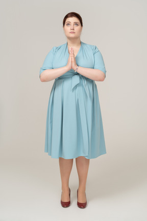 Front view of a woman in blue dress making praying gesture