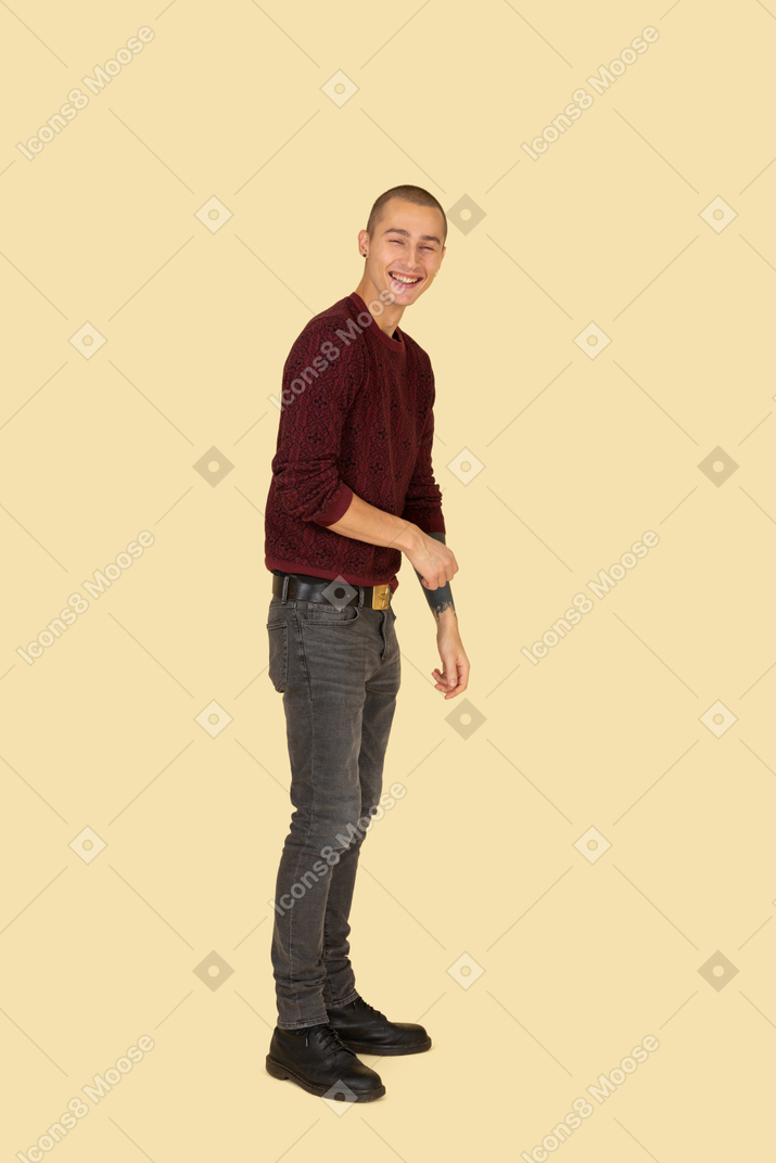 Seitenansicht eines jungen lachenden mannes im roten pullover, der kopf dreht