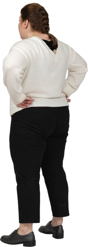Vista posteriore di una donna grassoccia in abiti casual in piedi con le mani sui fianchi
