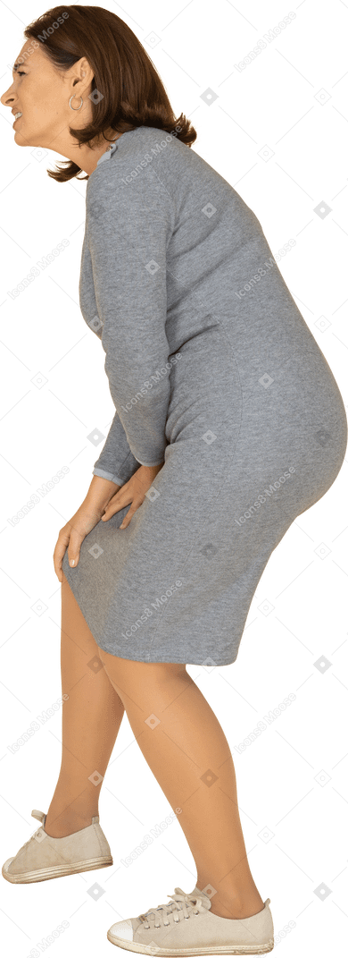 一个穿着灰色连衣裙的女人抚摸膝盖的侧视图
