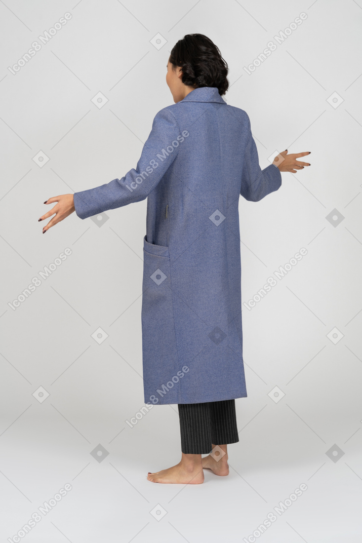 一个穿着外套的女人张开双臂的后视图