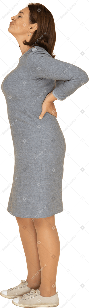 Vue latérale d'une femme en robe grise faisant des grimaces