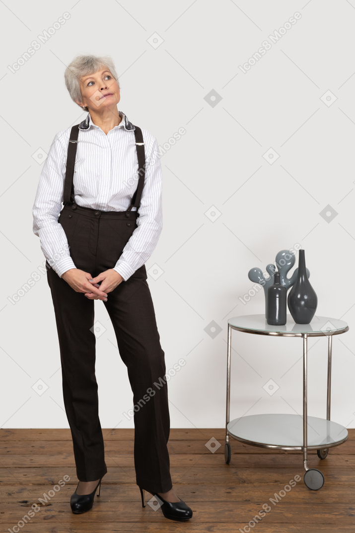 Front view of a dreaming old lady in office clothing putting hands together