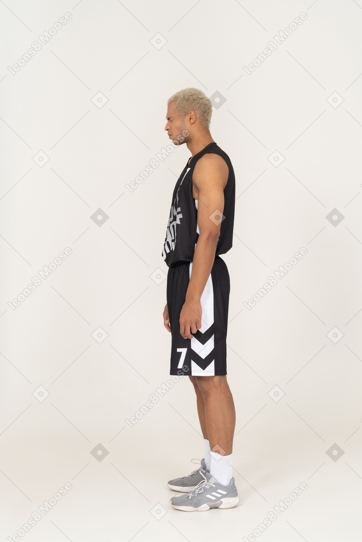 Vista lateral de un joven jugador de baloncesto masculino disgustado asegurando sus ojos