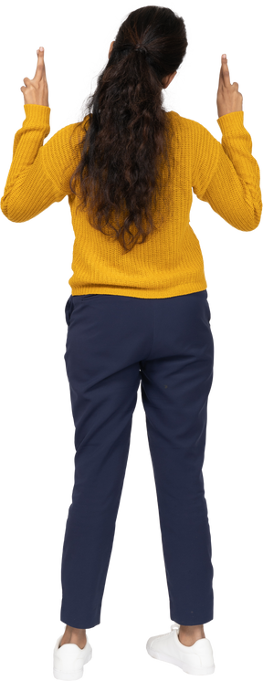 Rear view of a girl in casual clothes posing with crossed fingers