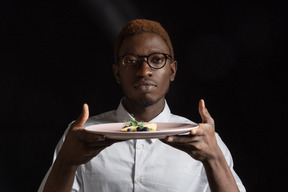 Close-up a waiter dressed in a white shirt demonstrating the dish