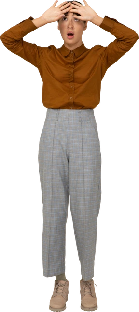 Front view of a shocked young asian female in breeches and blouse touching head